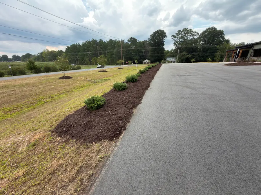 Commercial mulch installation along a parking lot sidewalk at a Kannapolis, NC business property