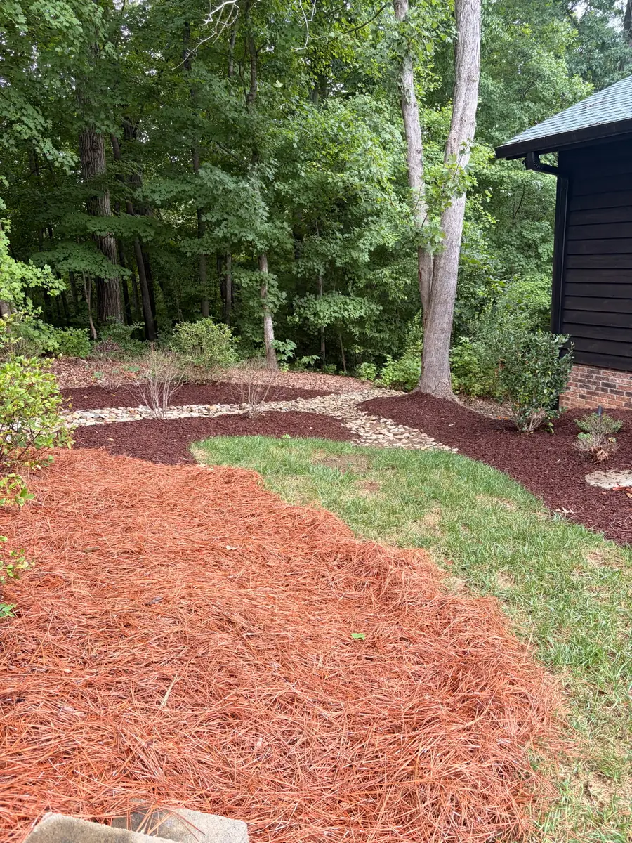 Black hardwood mulch bed installation along a hedge line in Concord, NC