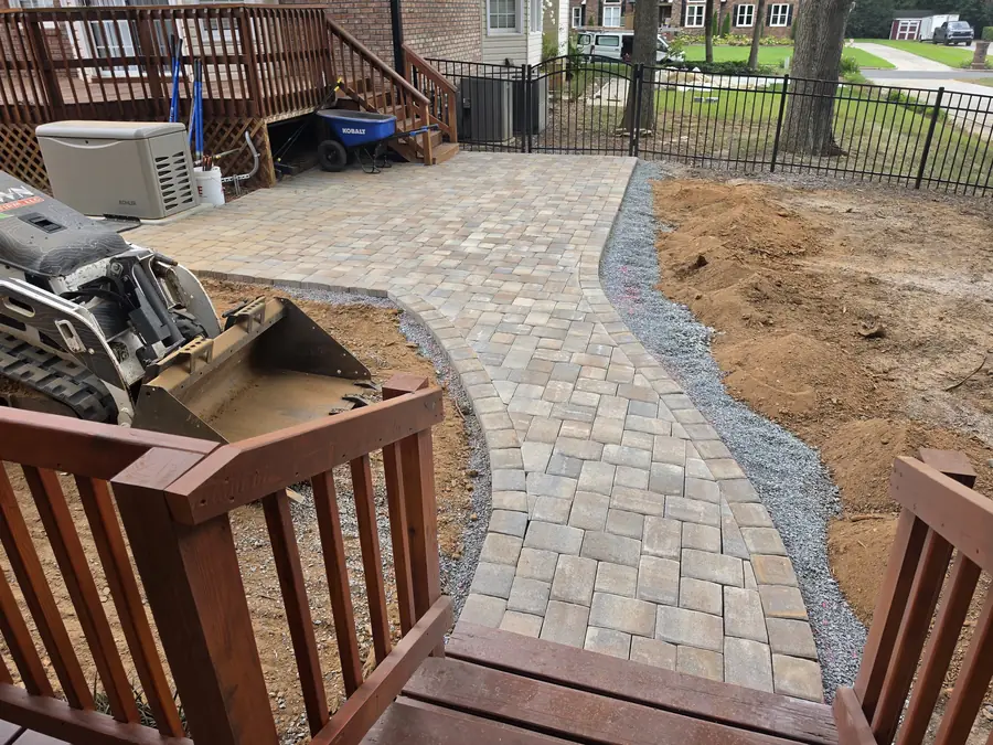 Curved paver walkway through a manicured backyard leading to a brick home in Kannapolis, NC