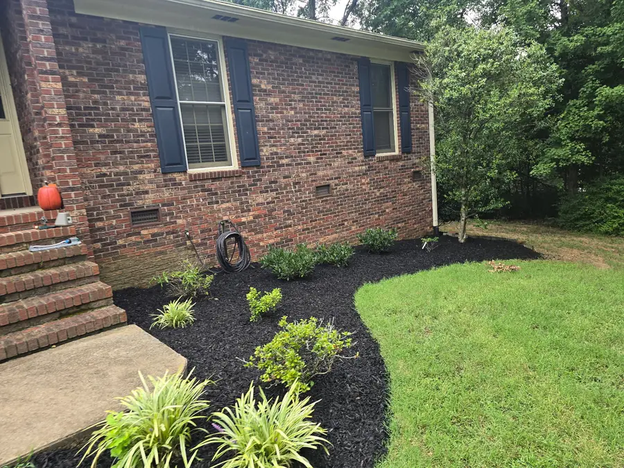 Pine straw mulch installation around a stone dry creek bed in Concord, NC